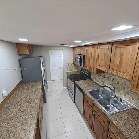 a kitchen with stainless steel appliances granite countertop a sink a stove and a refrigerator