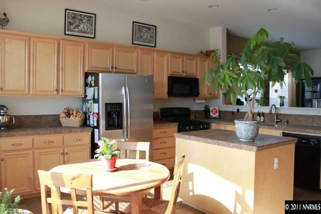 10680 Eagle Falls Way Reno, NV 89521 - Photo 4 of 8 a kitchen with stainless steel appliances granite countertop a refrigerator a stove a sink a dining table and chairs