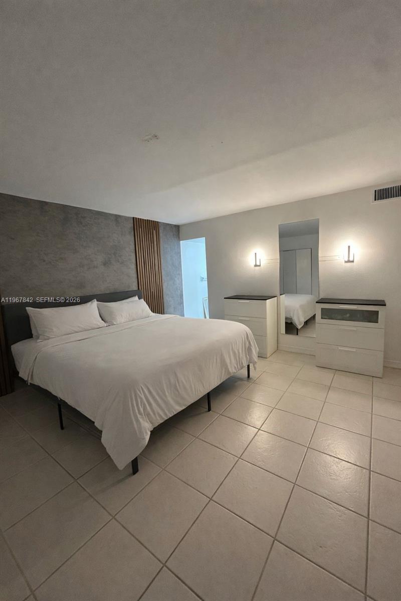 283 Woodland Road, Unit 283 Palm Springs, FL 33461 - Photo 14 of 28 a bedroom with a bed and a lamp