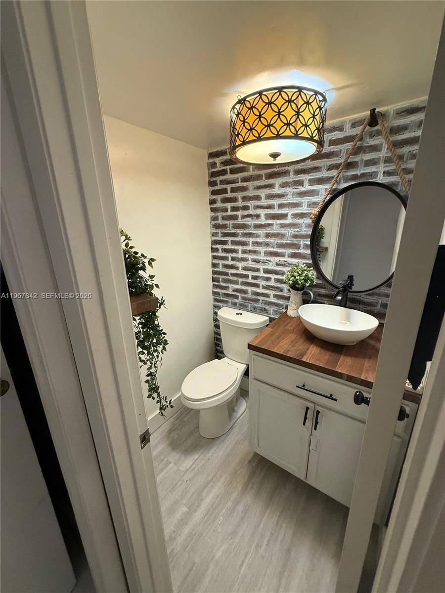 283 Woodland Road, Unit 283 Palm Springs, FL 33461 - Photo 9 of 28 a bathroom with a granite countertop toilet sink and mirror