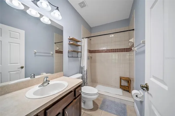 a bathroom with a sink a toilet a mirror and shower