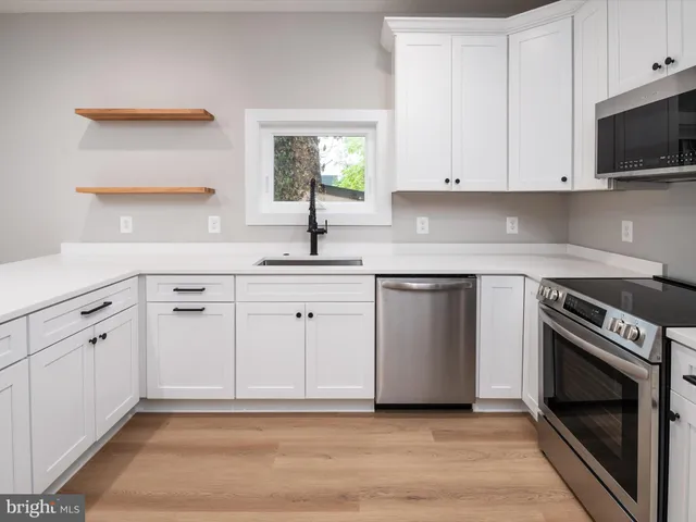 a kitchen with white cabinets appliances and sink