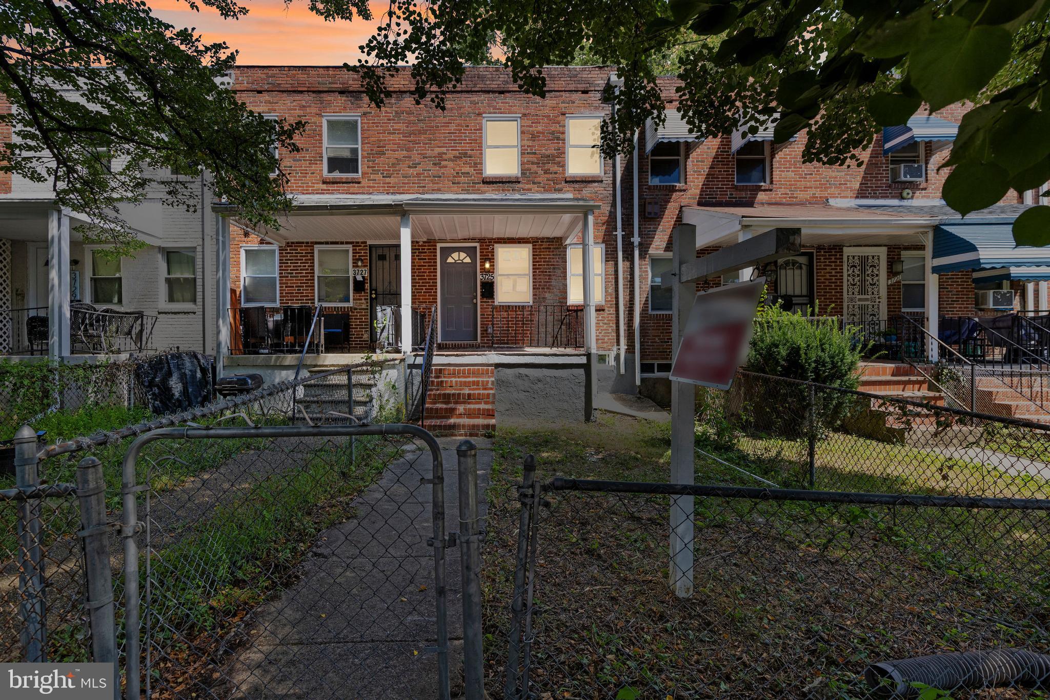 a view of a brick house with large windows plants and large trees