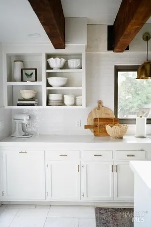 a kitchen with white cabinets and window