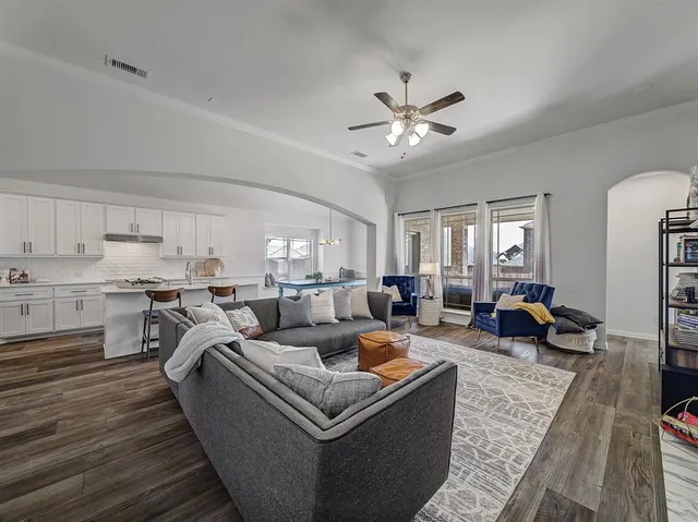 a living room with furniture kitchen view and a wooden floor