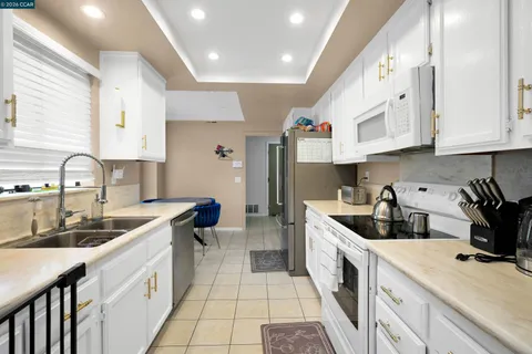 a kitchen with granite countertop white cabinets and white appliances