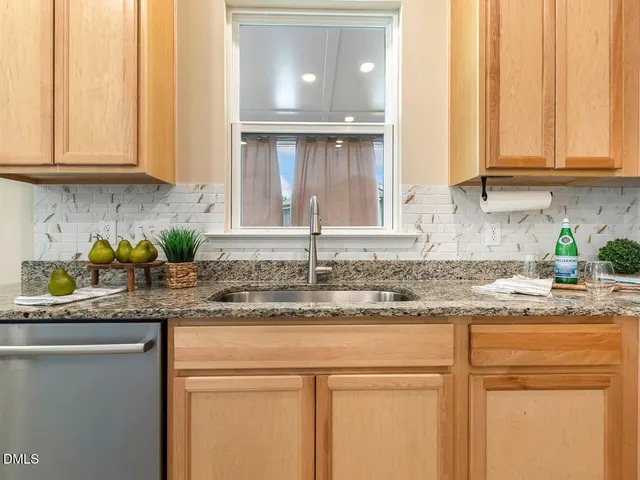 a kitchen with granite countertop stainless steel appliances a stove a sink and cabinets