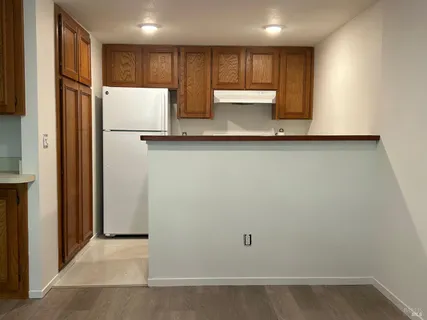 a view of kitchen with refrigerator and white cabinets