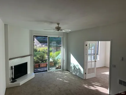 a view of a livingroom with a fireplace a ceiling fan and windows