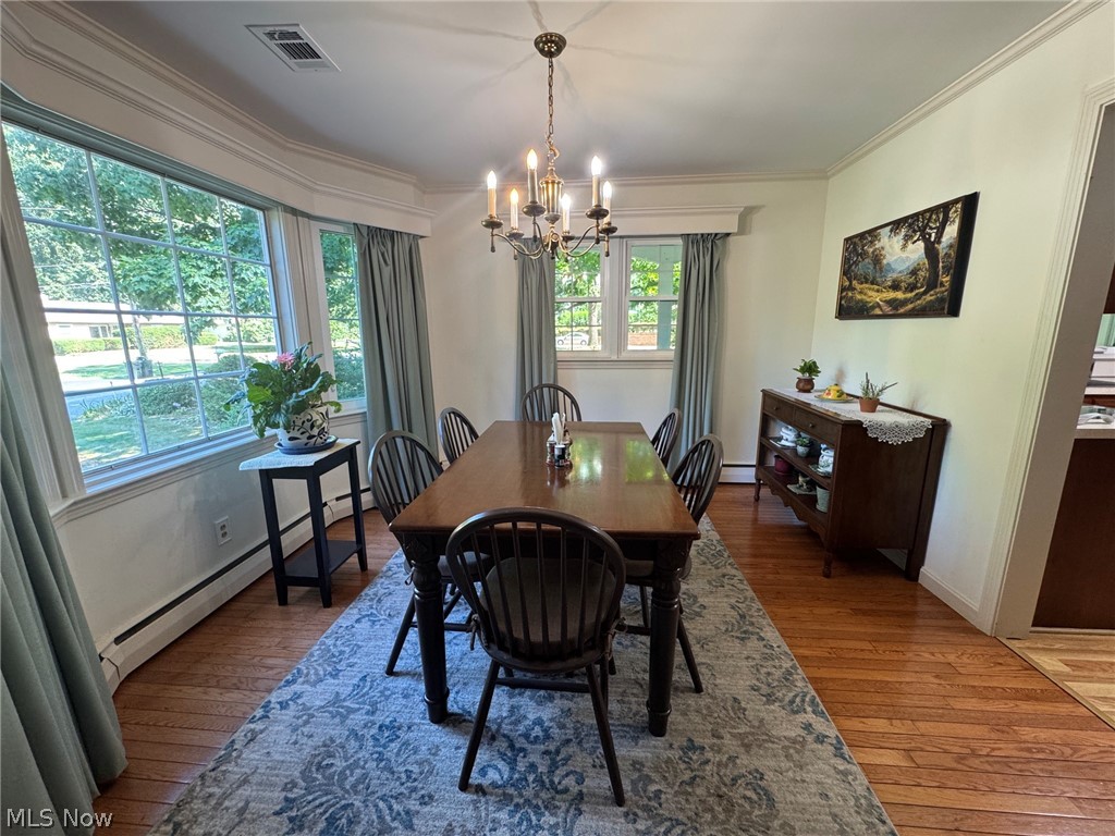 296 Fairfield Road Painesville, OH 44077 - Photo 20 of 48 Hardwood flooring throughout featuring a large bay window, crown molding, and a chandelier with candle-style lights