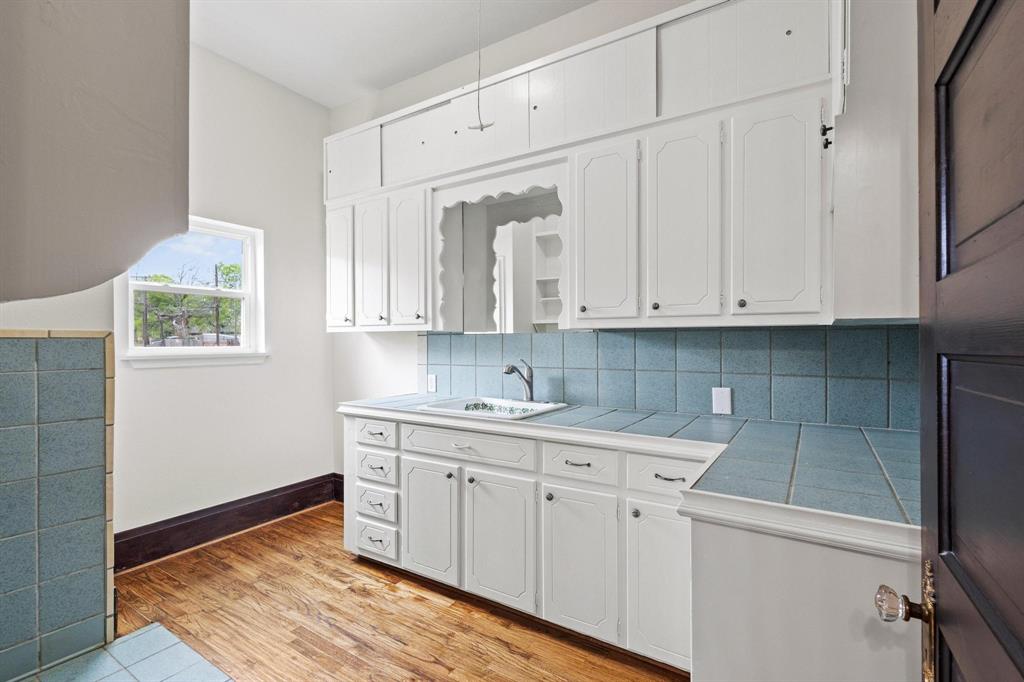 1001 West Morton Street Denison, TX 75020 - Photo 32 of 37 a kitchen with white cabinets and sink