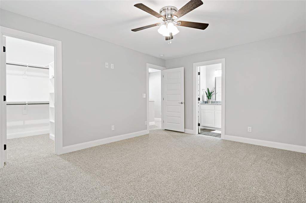 526 West Elm Street Denison, TX 75020 - Photo 13 of 17 Unfurnished bedroom featuring a spacious closet, connected bathroom, light carpet, and ceiling fan