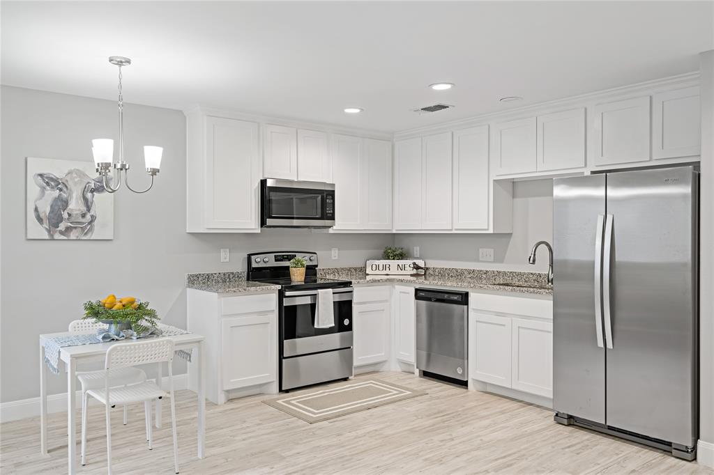 526 West Elm Street Denison, TX 75020 - Photo 5 of 17 Kitchen featuring appliances with stainless steel finishes, light wood-type flooring, decorative light fixtures, white cabinets, and recessed lighting