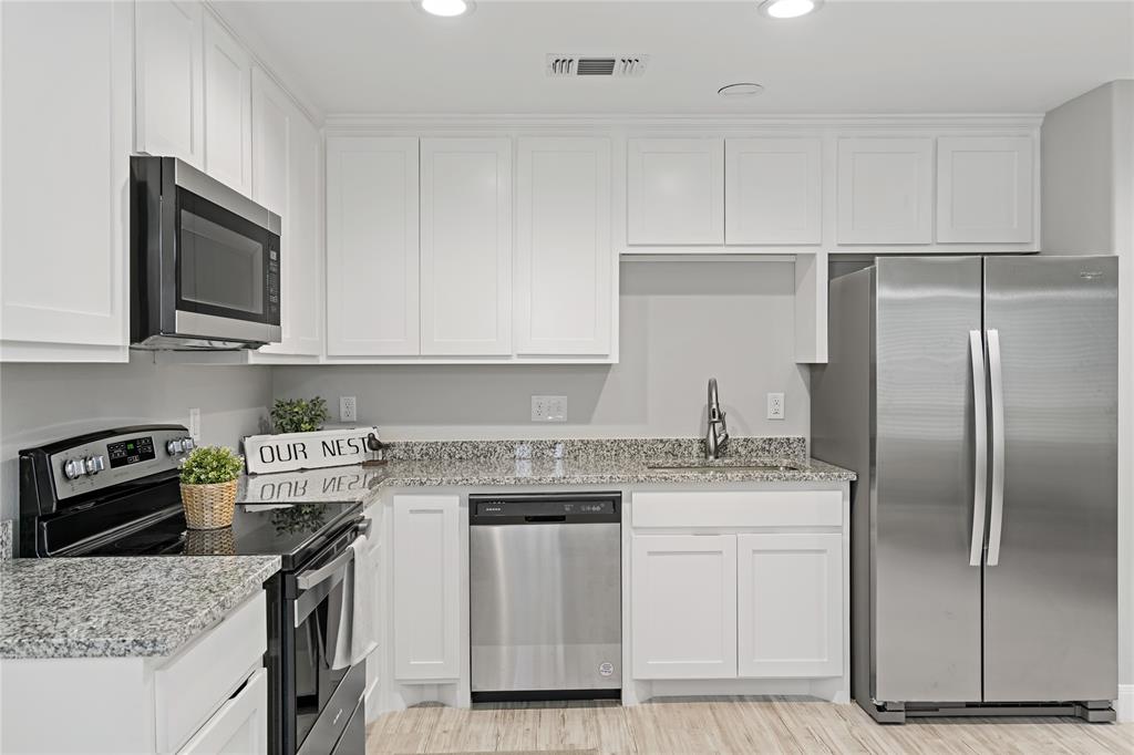 526 West Elm Street Denison, TX 75020 - Photo 6 of 17 Kitchen with stainless steel appliances, white cabinets, light stone counters, light wood-type flooring, and recessed lighting