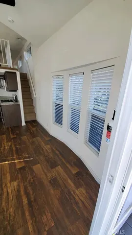 a view of an empty room with wooden floor and stairs