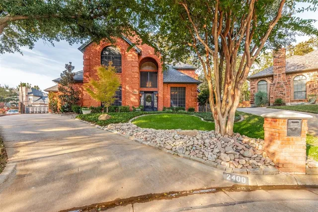 a front view of a house with a garden and trees