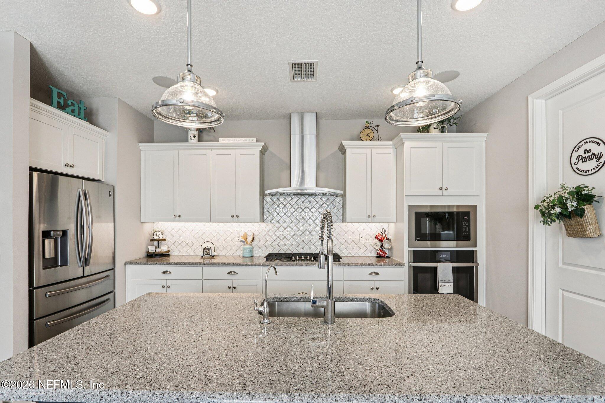 73 Andesite Trail Ponte Vedra, FL 32081 - Photo 13 of 42 a kitchen with kitchen island stainless steel appliances a stove a table and chairs