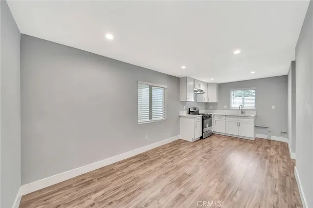 a room with wooden floors and kitchen view