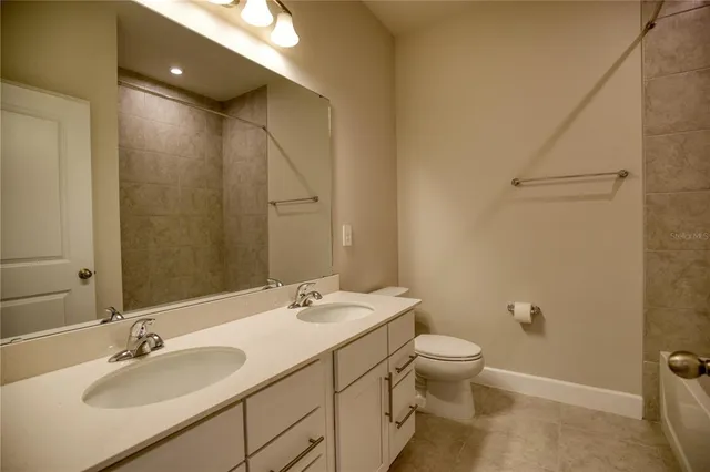 a bathroom with a double vanity sink toilet and a mirror