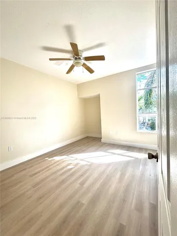 an empty room with wooden floor fan and windows