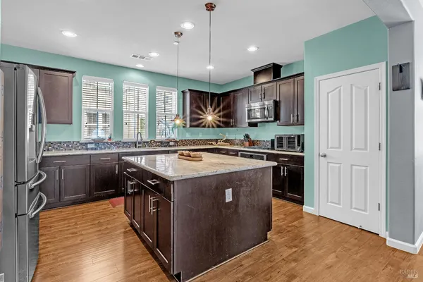 a kitchen with stainless steel appliances granite countertop a refrigerator and a stove top oven