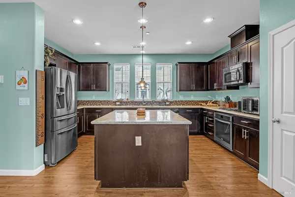 a kitchen with stainless steel appliances granite countertop a sink a stove and a refrigerator