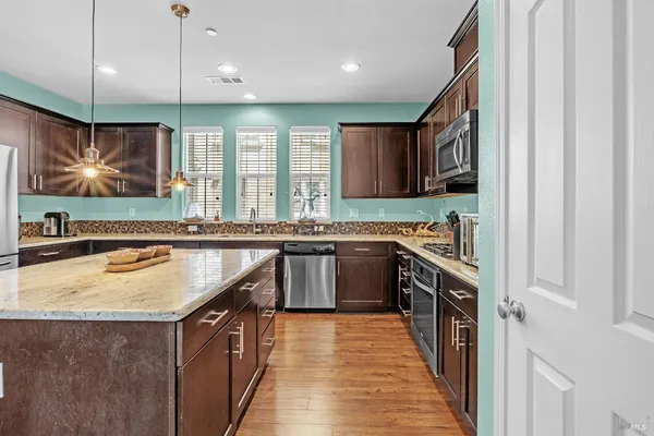 a kitchen with stainless steel appliances granite countertop a sink a stove and a wooden cabinets
