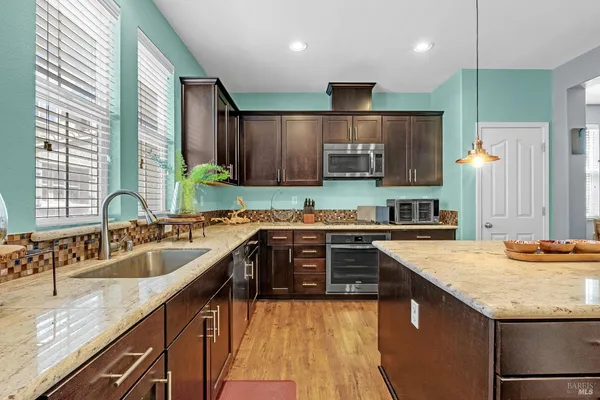 a kitchen with stainless steel appliances granite countertop a sink refrigerator and cabinets