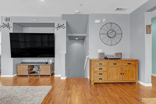 a view of a living room with wooden floor and a ceiling fan