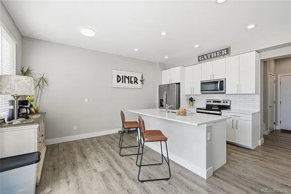 a kitchen with a sink a microwave a refrigerator and wooden floor