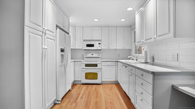 a kitchen with white cabinets and white appliances