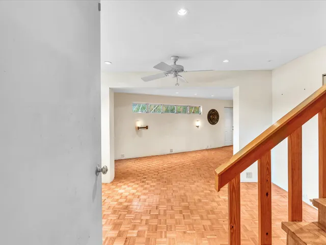 a view of an empty room with wooden floor and stairs