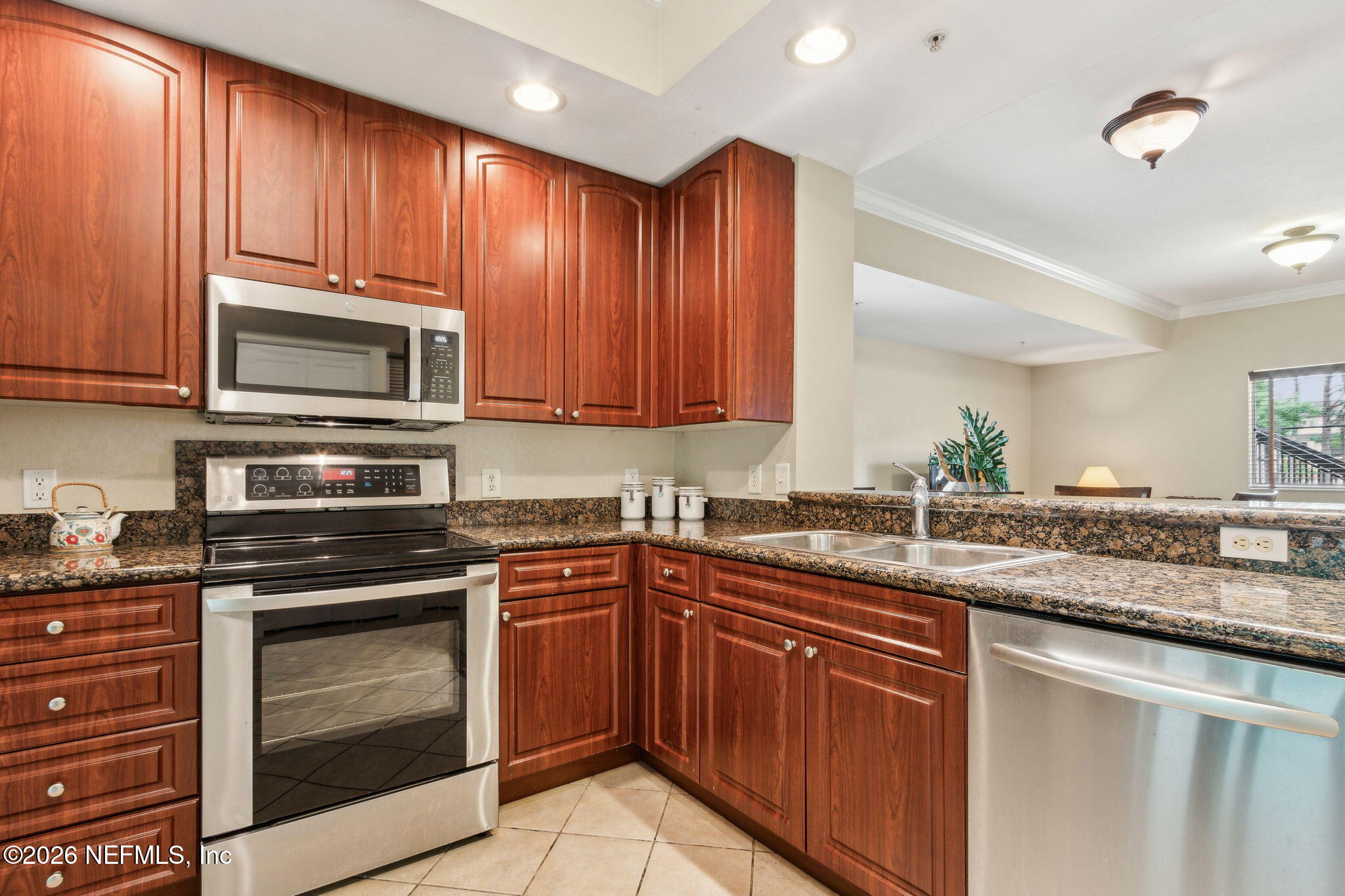 9745 Touchton Road, Unit 1205 Jacksonville, FL 32246 - Photo 7 of 20 a kitchen with stainless steel appliances granite countertop wooden cabinets and a stove top oven