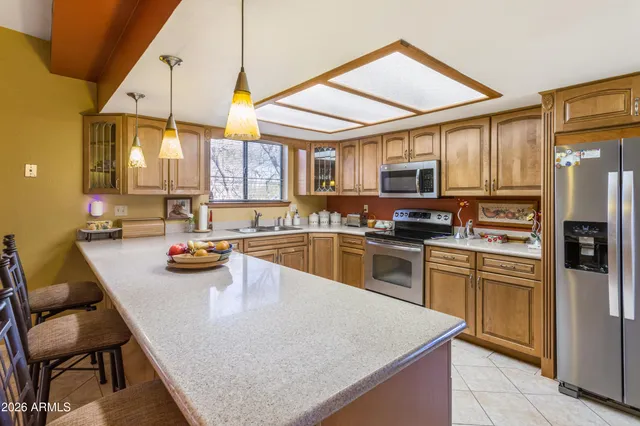 a kitchen with a refrigerator a stove top oven a sink a dining table and chairs