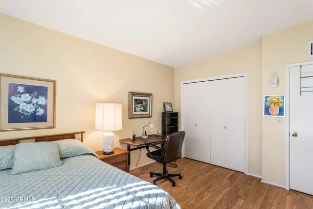 a bedroom with a bed a desk and chair with wooden floor