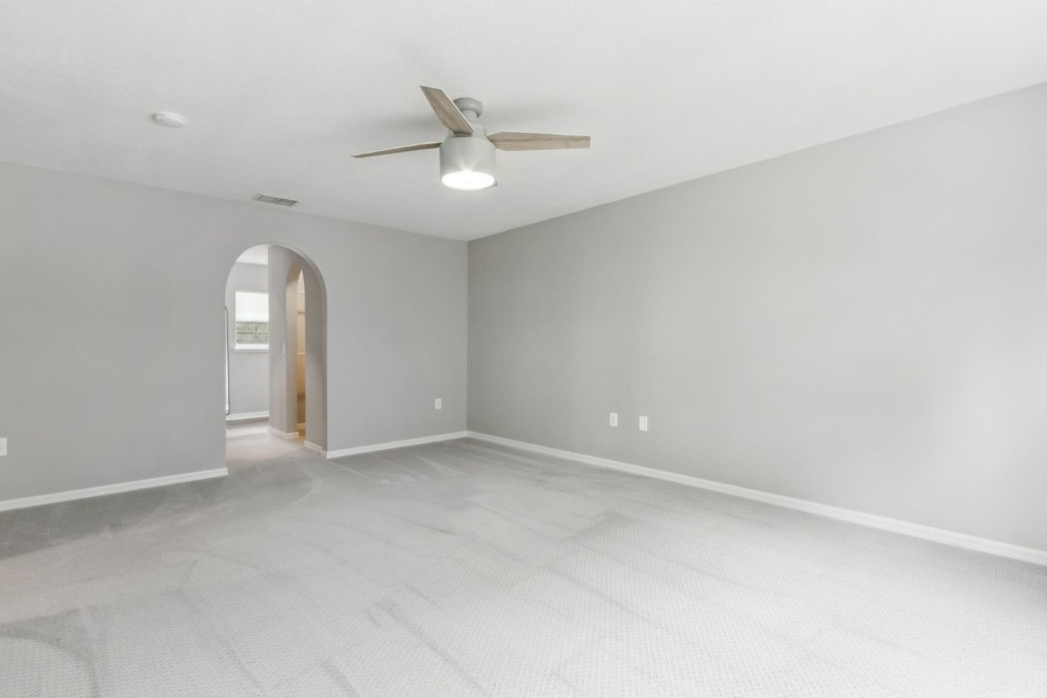 76367 Longleaf Loop Yulee, FL 32097 - Photo 18 of 49 an empty room with a chandelier fan and windows