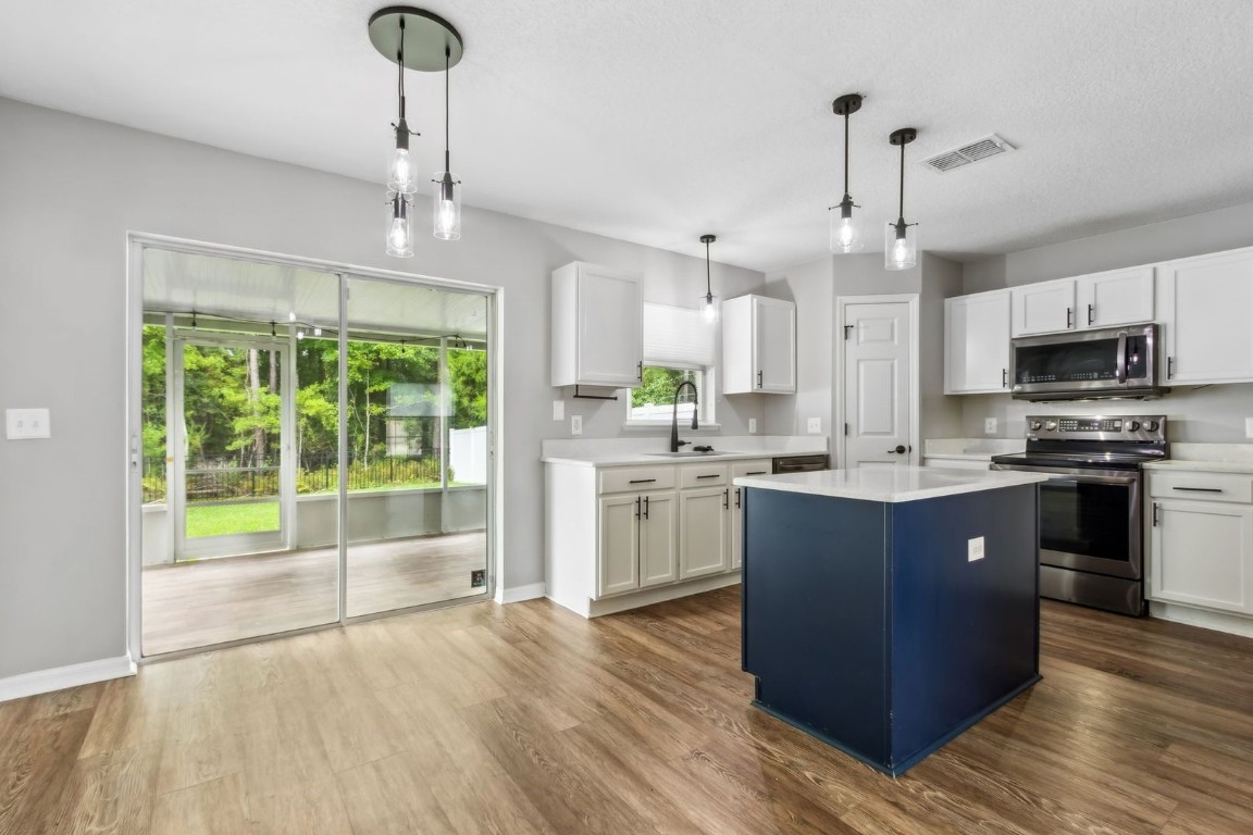 76367 Longleaf Loop Yulee, FL 32097 - Photo 8 of 49 a large kitchen with stainless steel appliances granite countertop a stove a sink dishwasher a refrigerator and a wooden floor