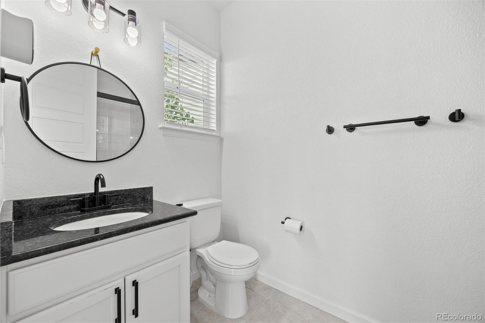6346 Rockingham Way Castle Pines, CO 80108 - Photo 15 of 43 a bathroom with a granite countertop sink a toilet and a mirror
