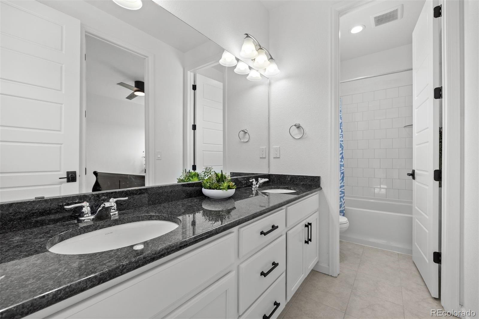 6346 Rockingham Way Castle Pines, CO 80108 - Photo 24 of 43 a bathroom with a granite countertop double vanity sink a mirror and a