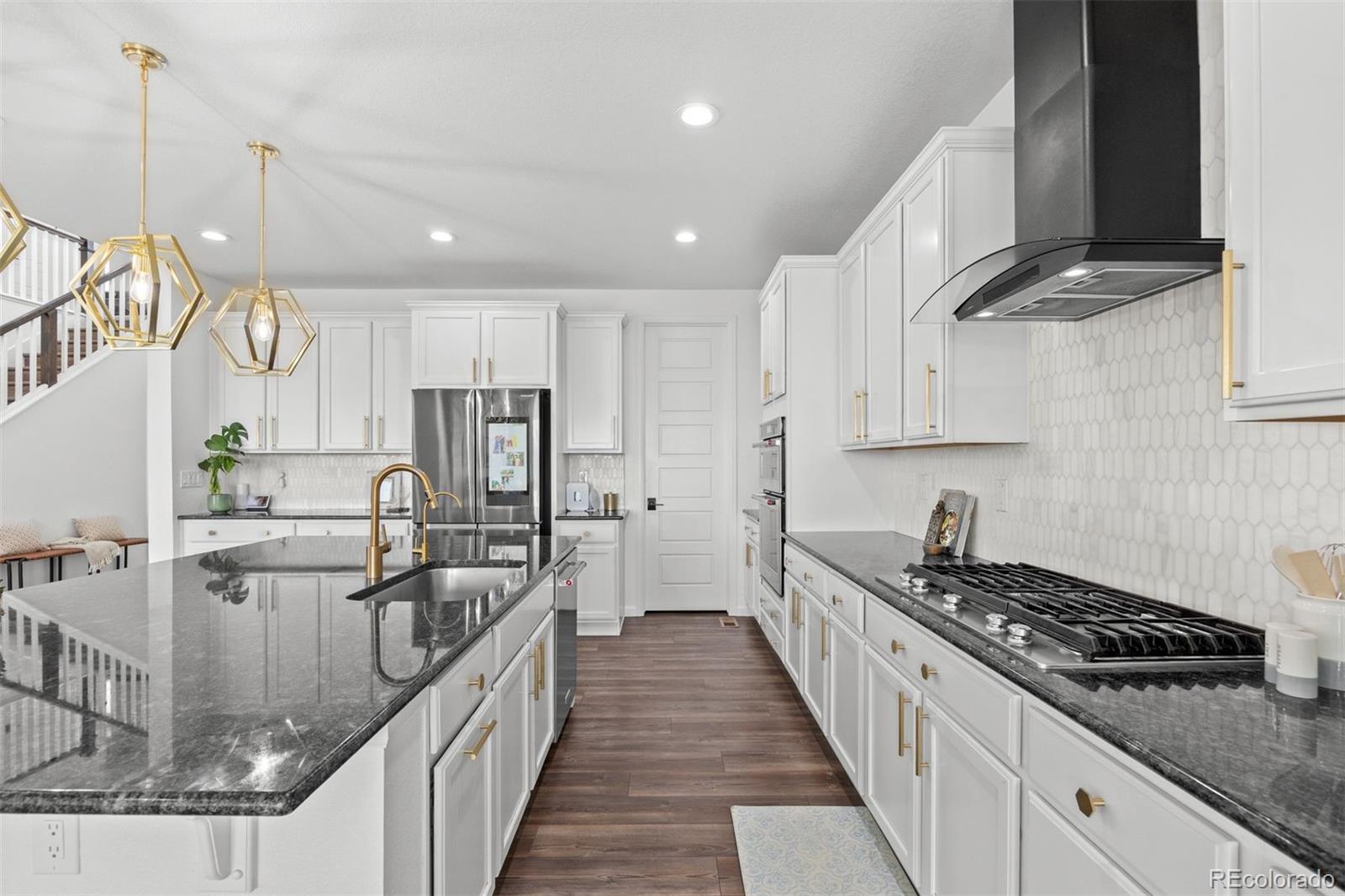 6346 Rockingham Way Castle Pines, CO 80108 - Photo 9 of 43 a kitchen with kitchen island stainless steel appliances a sink a stove top oven a counter space and cabinets