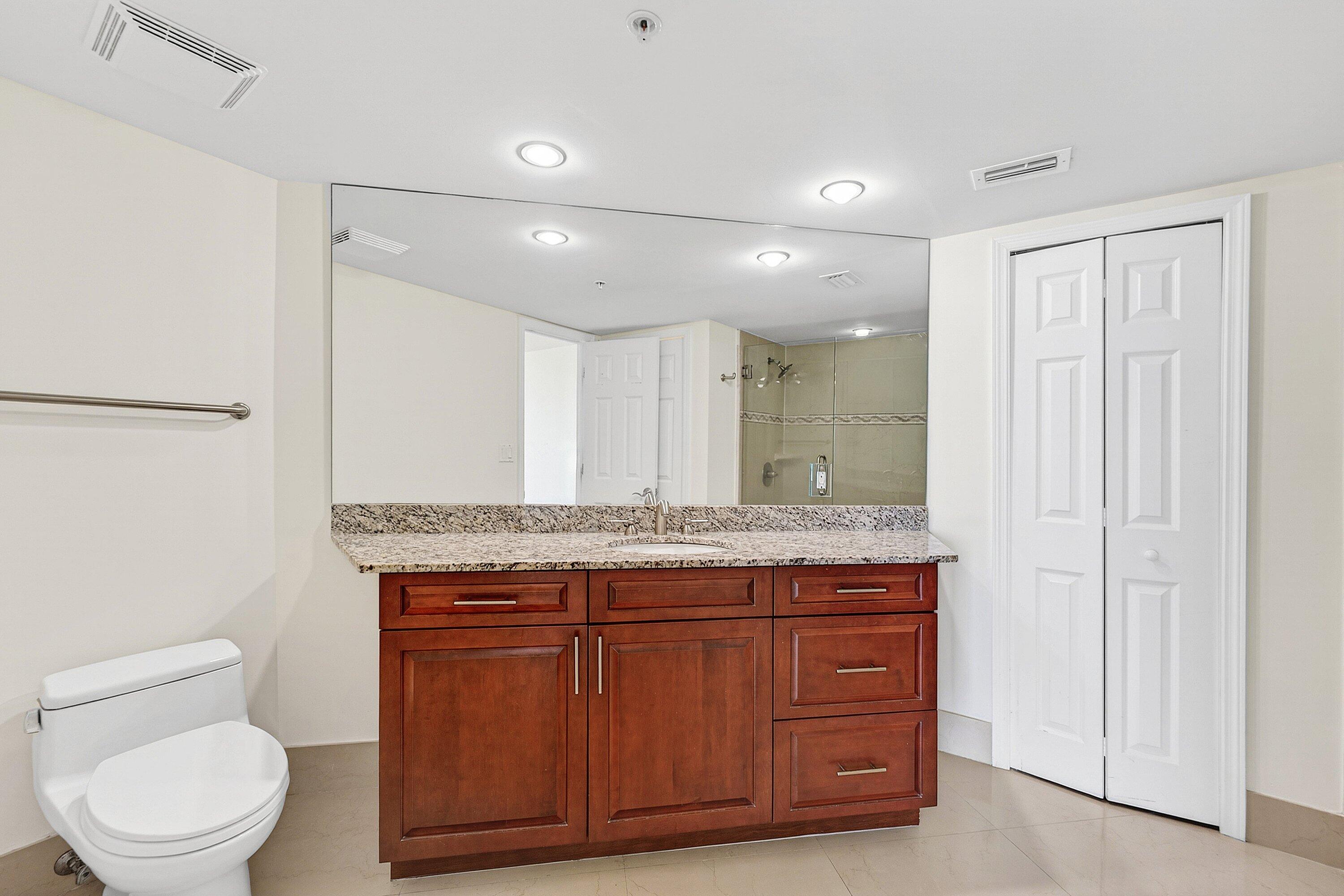 3000 North Ocean Drive, Unit 8F Singer Island, FL 33404 - Photo 9 of 66 a bathroom with a granite countertop sink a toilet and a mirror