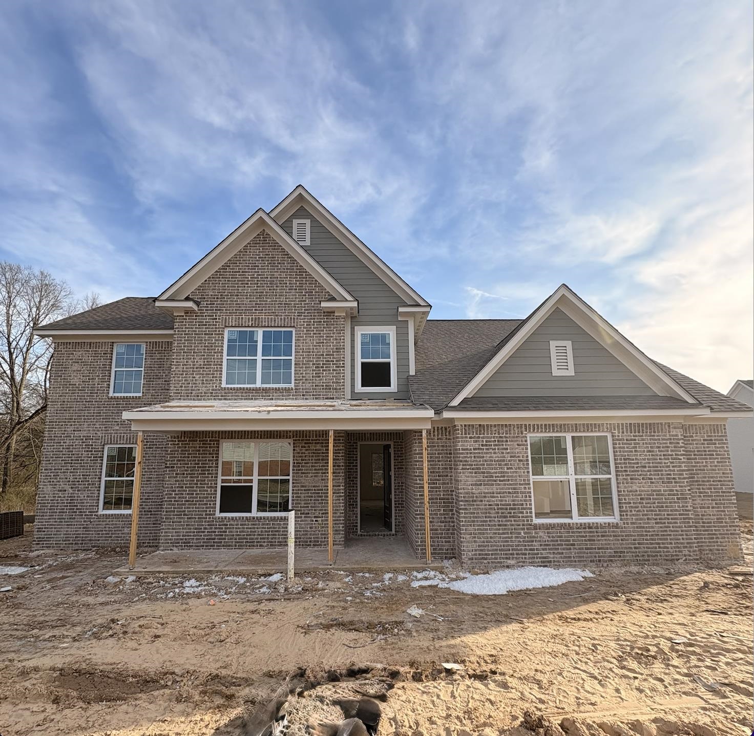 View of front of home featuring brick siding, a porch, and roof with shingles
