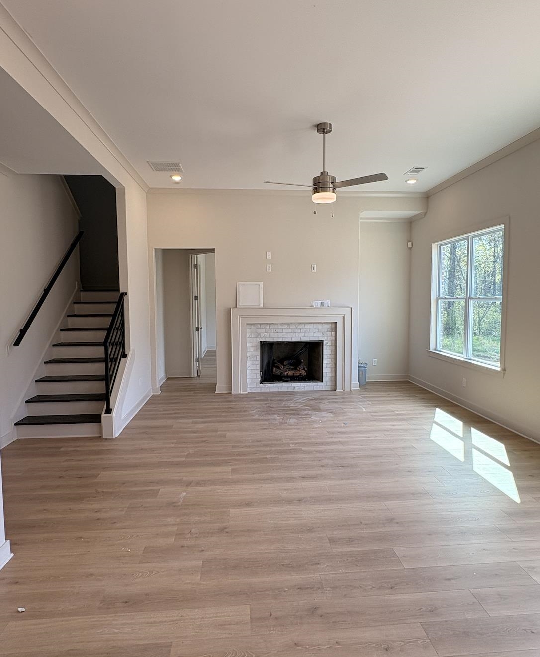 5054 Summers Road Arlington, TN 38002 - Photo 6 of 11 Unfurnished living room featuring a tiled fireplace, light wood-style flooring, a ceiling fan, and crown molding