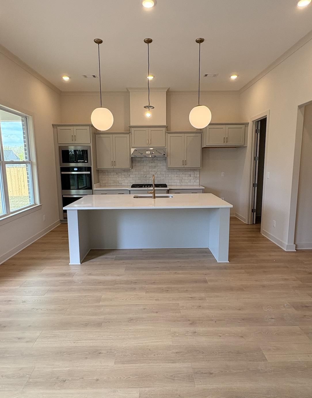 5054 Summers Road Arlington, TN 38002 - Photo 7 of 11 Kitchen with gray cabinets, decorative light fixtures, a kitchen island with sink, light wood-style flooring, and a kitchen bar