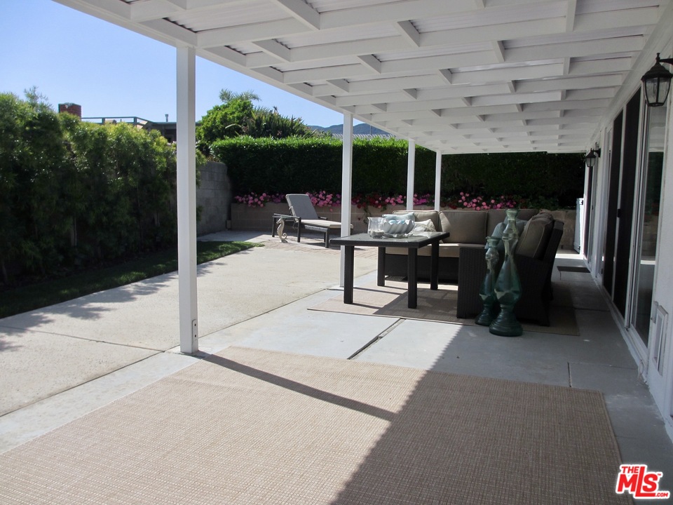3641 Surfwood Road Malibu, CA 90265 - Photo 20 of 29 a view of a patio with a dining table and chairs under an umbrella