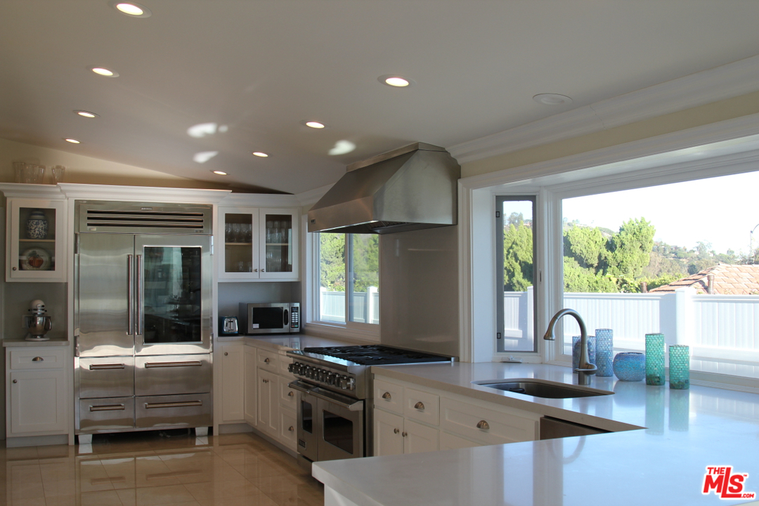 3641 Surfwood Road Malibu, CA 90265 - Photo 6 of 29 a kitchen with stainless steel appliances granite countertop a stove a sink a refrigerator and a dining table with garden view