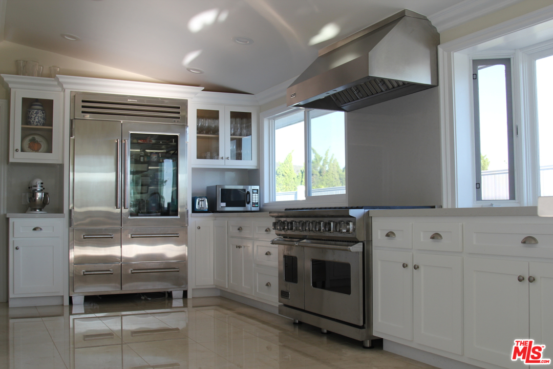 3641 Surfwood Road Malibu, CA 90265 - Photo 7 of 29 a kitchen with a stove and white cabinets