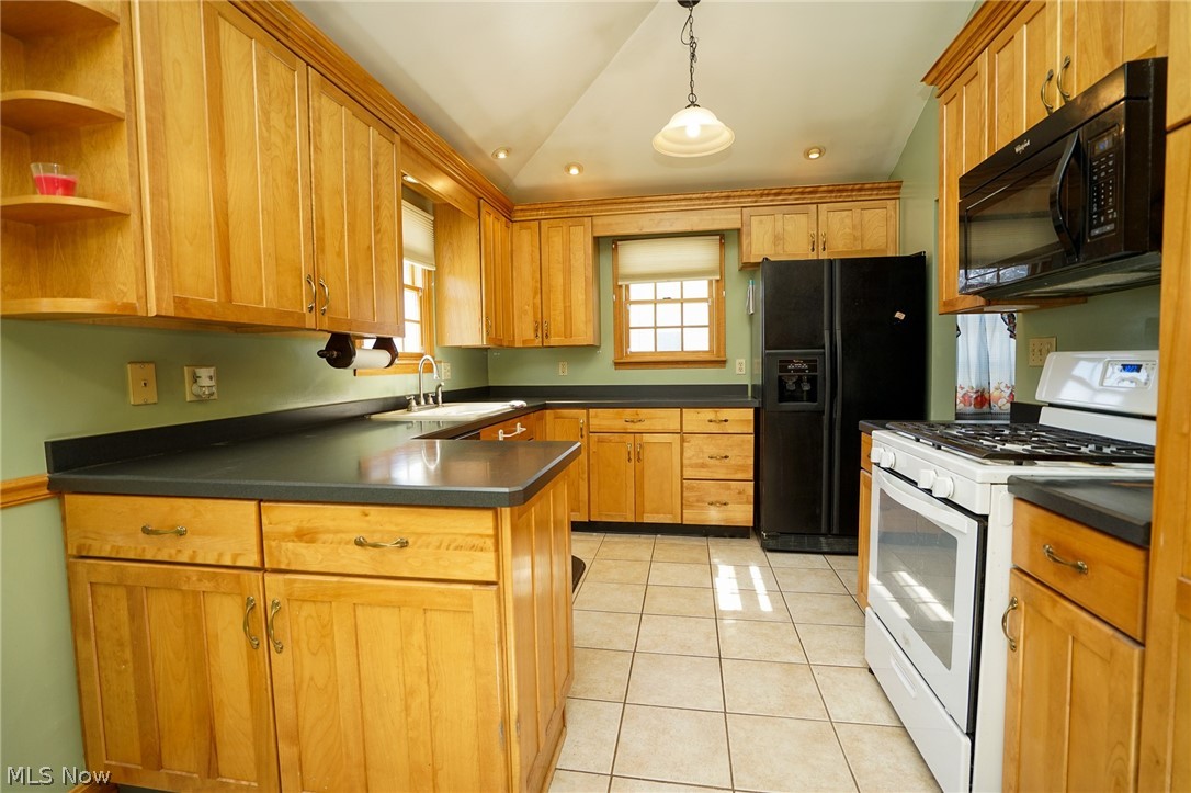 453 Omar Street Struthers, OH 44471 - Photo 12 of 27 Kitchen featuring black appliances, lofted ceiling, dark countertops, a peninsula, and light tile patterned floors