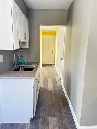a kitchen with a sink and wooden floor