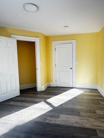 a view of an empty room with wooden floor and closet